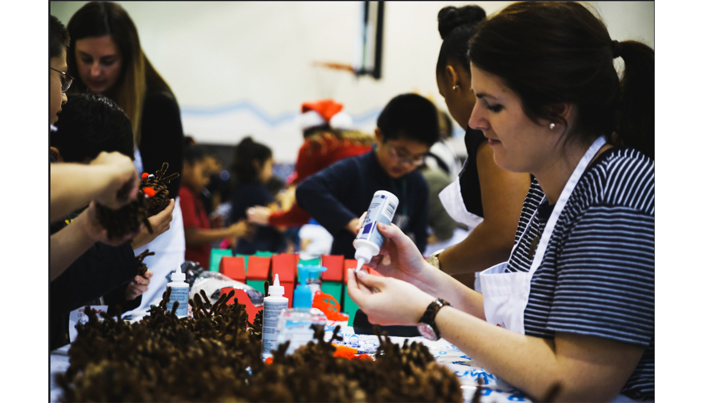 (L-R) Sarah Moore, Trinisha Sowells (turned away) and Anna Mitchell help children assemble Christmas craft presents. Not pictured: Geri Powell, Gibran Villalobos and Micki Washington. -