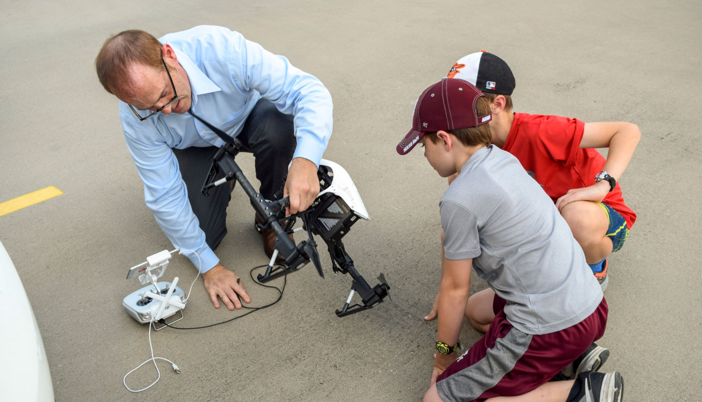 Steve Meyers showing children how to get a drone-camera off the ground, Brian Roeder (children) -