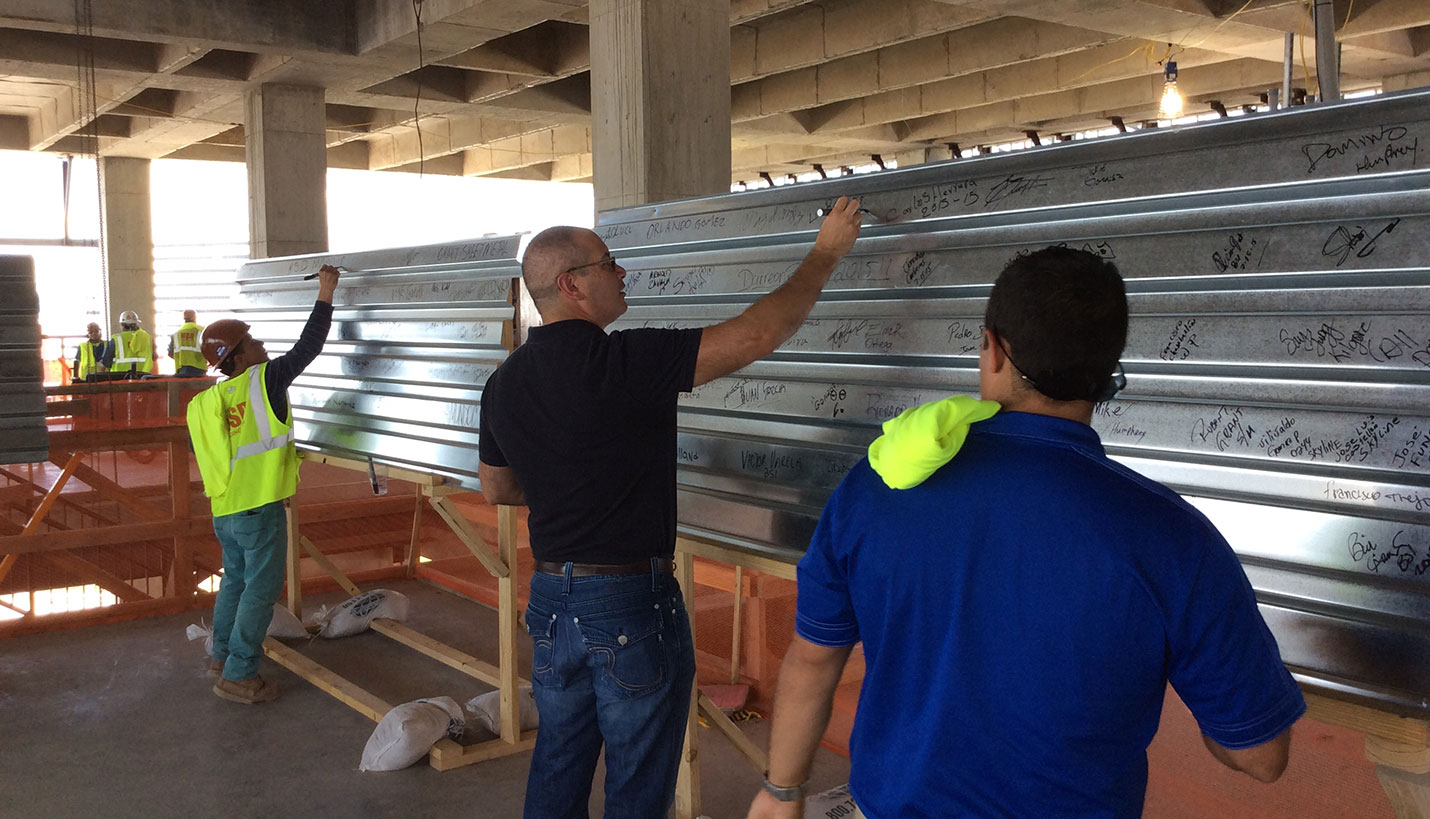 Luis Reyes, Page Senior Mechanical Engineer, puts his imprint on a section of decking to be installed on the roof. -