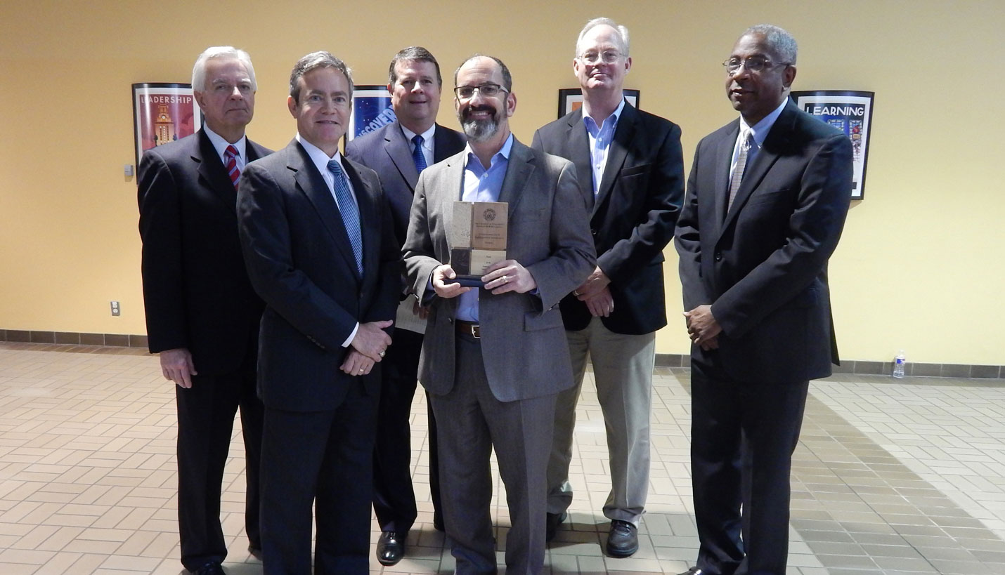 Page Principal Daniel Brooks holding the HUB award. -